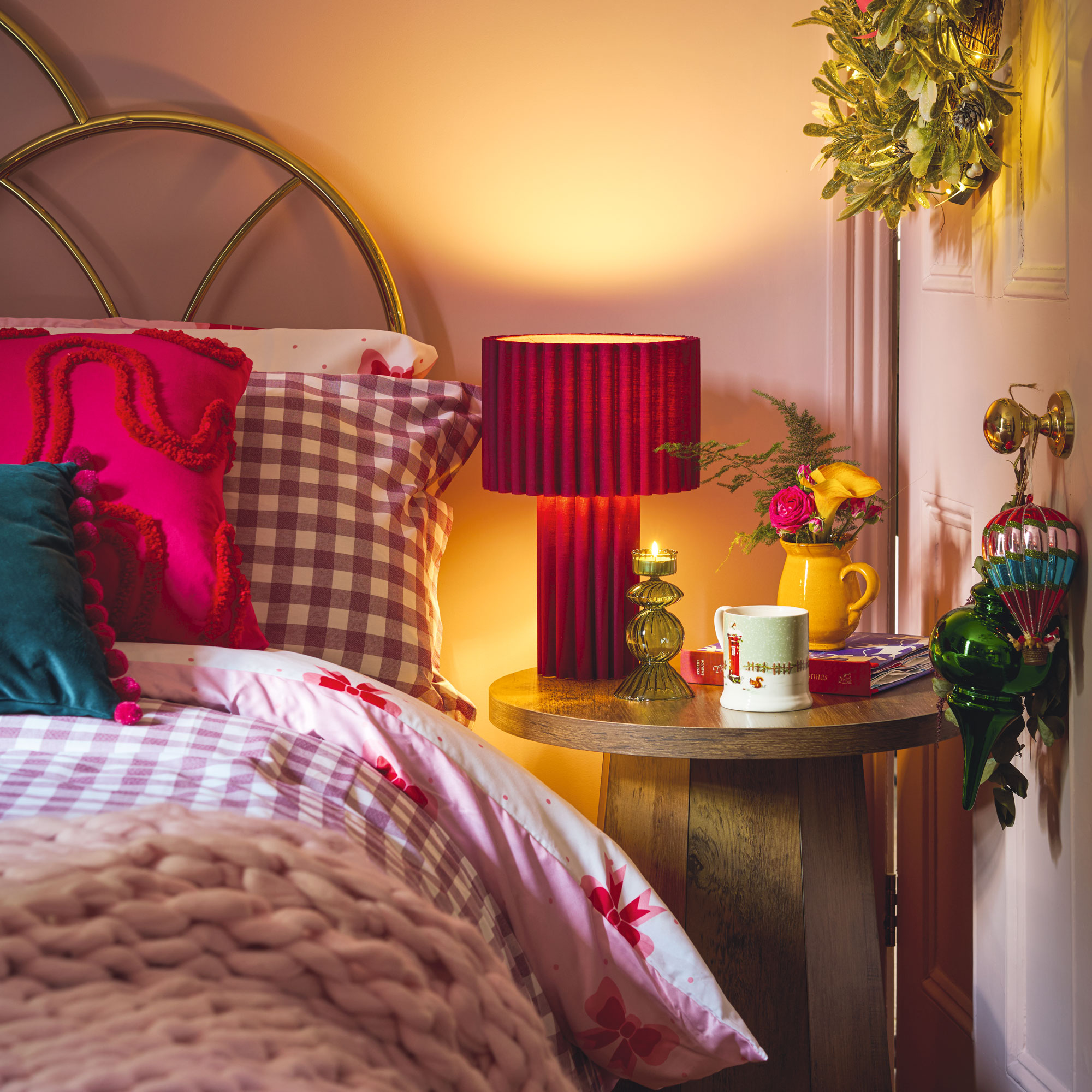 Pink bedroom with wooden side table and red bedside lamp