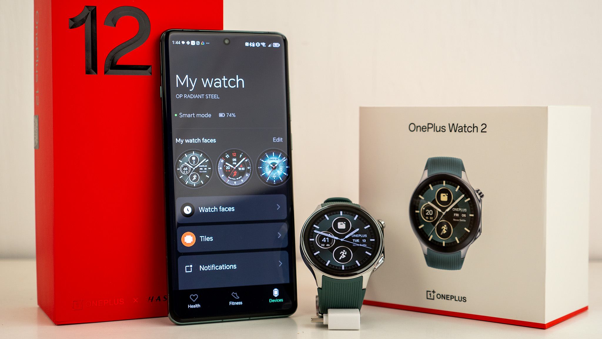 The OnePlus Watch 2 with a OnePlus 12 phone and their respective boxes