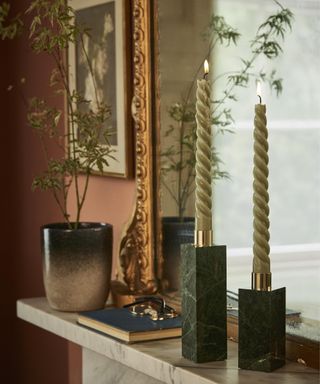 A set of twisted candles on a mantelpiece with brass framed mirror decor