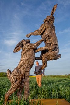 Sculptor Hamish Mackie with his bronze Hares Monumental. ‘A sculpture should have its own power, then the viewer will feel an emotional response,’ says Hamish. Photo: Mark Williamson for Country Life