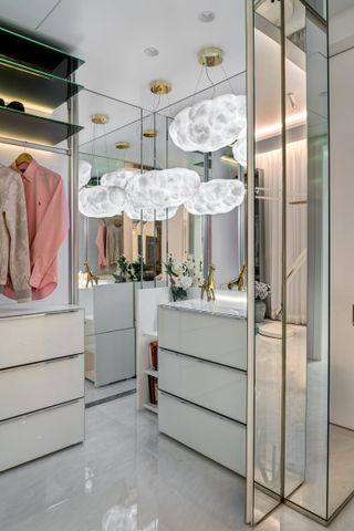 Mirrored walk-in closet with white storage chests