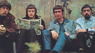 John Mayall's Bluesbreakers sitting against a wall, Eric Clapton reading a copy of the Beano comic.