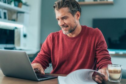 Middle-aged man using laptop at home. Working at home or surfing the net, resting in living room. Handsome businessman home office