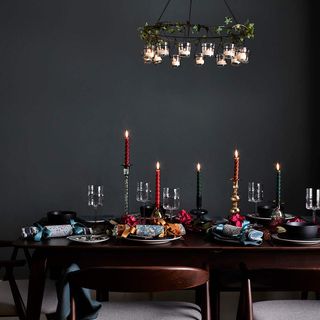 Green dining room with table decorated for Christmas with crackers and red and green candles