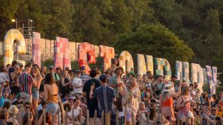 rowds gather below the Glastonbury sign to look the sunset during day one of Glastonbury Festival at Worthy Farm, Pilton