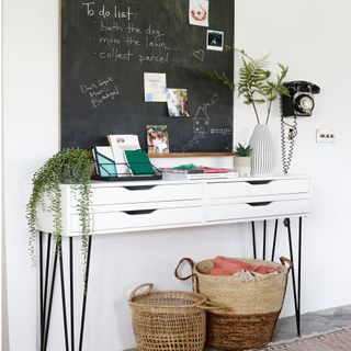 white sideboard with storage baskets underneath and black chalkboard above