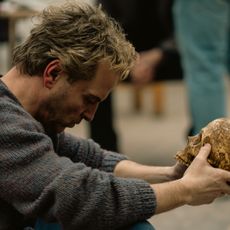 A blond man (Andrew Scott as Ian Charleson) sits in a rehearsal room while holding a weathered skull, in a still from 'Elsinore' one of the Best Drama Movies of 2026.