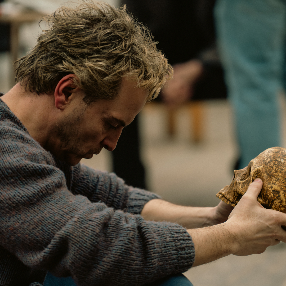 A blond man (Andrew Scott as Ian Charleson) sits in a rehearsal room while holding a weathered skull, in a still from 'Elsinore' one of the Best Drama Movies of 2026.