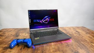 Asus ROG Strix G16 (G614FR) gaming laptop on a wooden desk against a gray background.