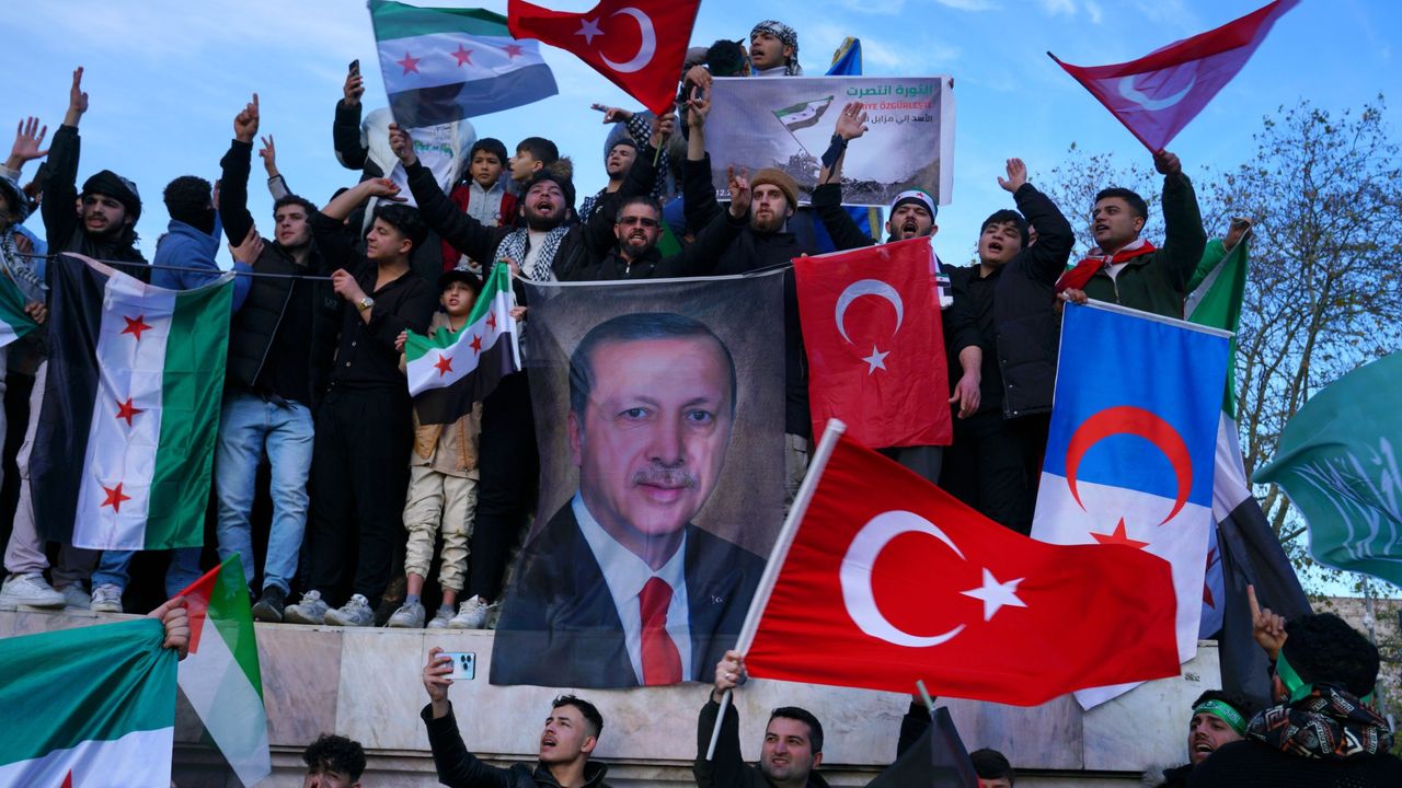 Syrians living in Turkey hold a large poster of Turkish President Recep Tayyip Erdogan after Syrian rebels announced that they have ousted President Bashar al-Assad