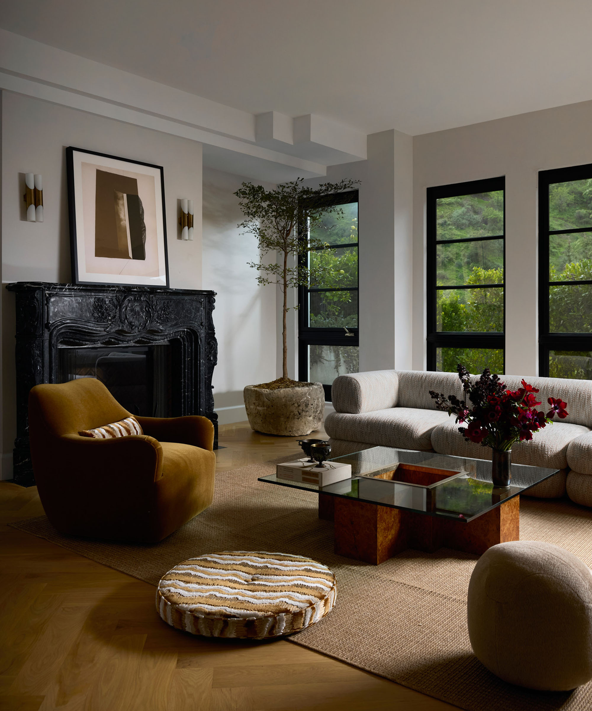 corner of a large living room with big windows and dark fireplace