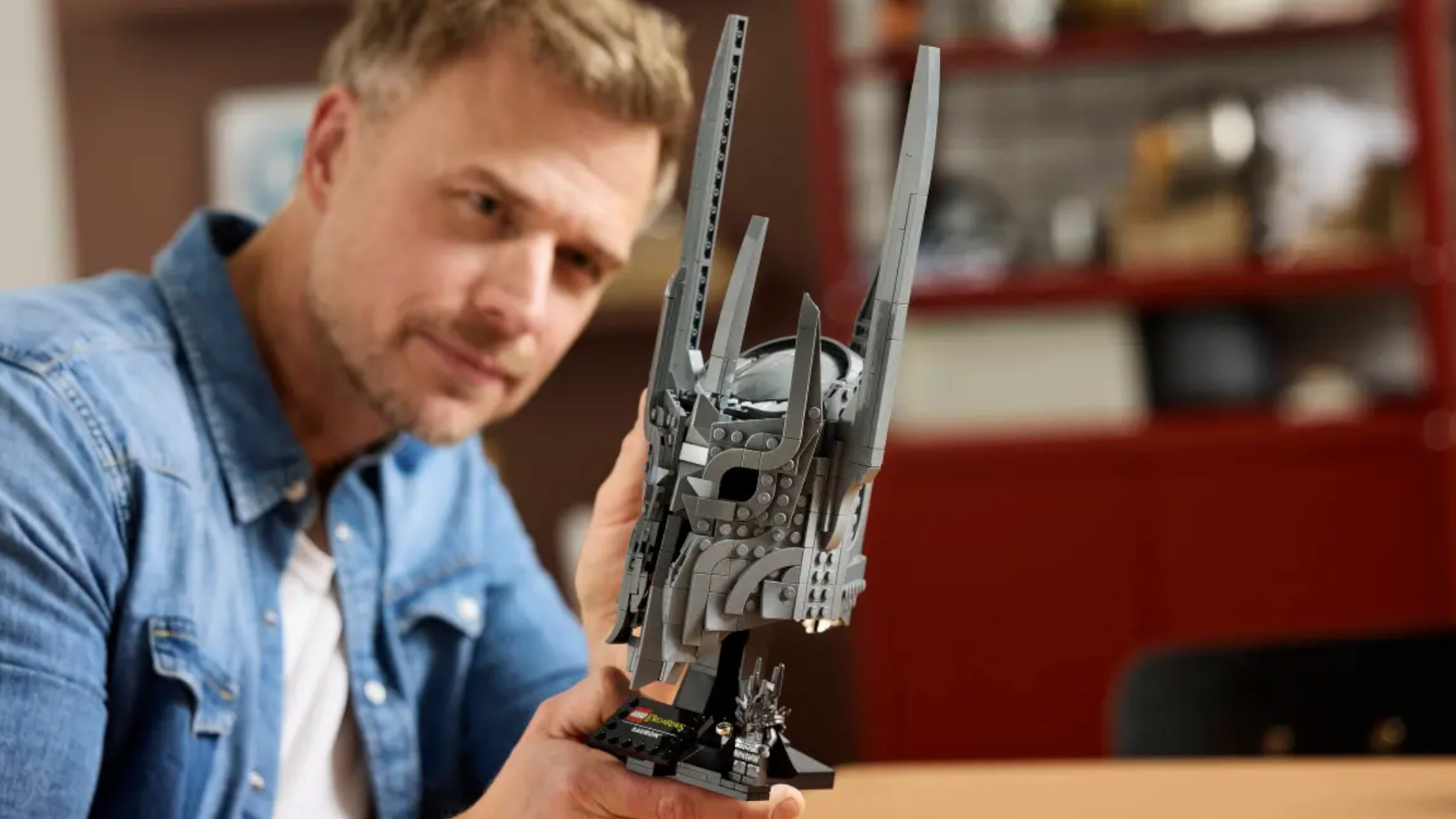 A man smiles while handling the Lego Sauron's helmet set