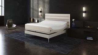 The new Sleep Number 360 smart bed on a cream colored faux leather frame and placed in a dark bedroom