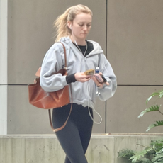 Sarah Pidgeon walks down the street in Brisbane wearing flared leggings with chunky trainers and a grey zip-up hoodie.