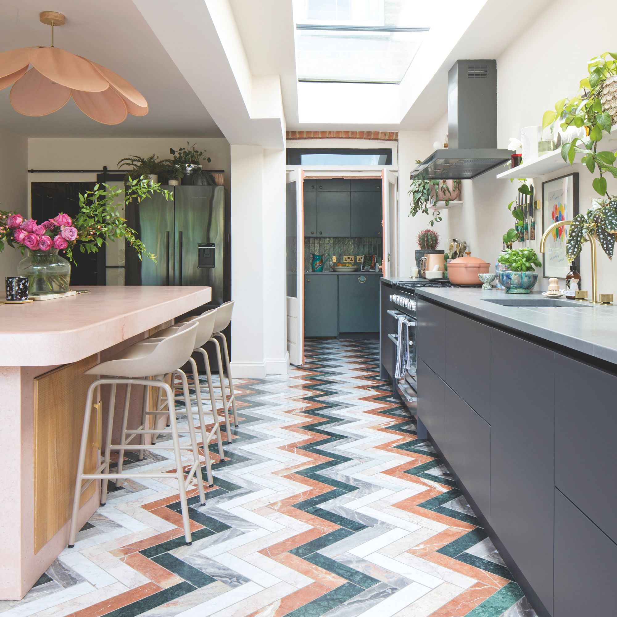 Kitchen with colourful tiled floor and grey cabinets on one side of the kitchen, with a kitchen island on the other