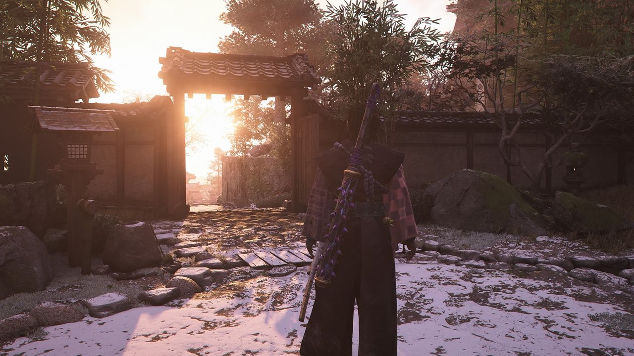 Assassin's Creed Shadows screenshot of Yasuke looking out towards a gate, with snow on the ground and sun streams shining through