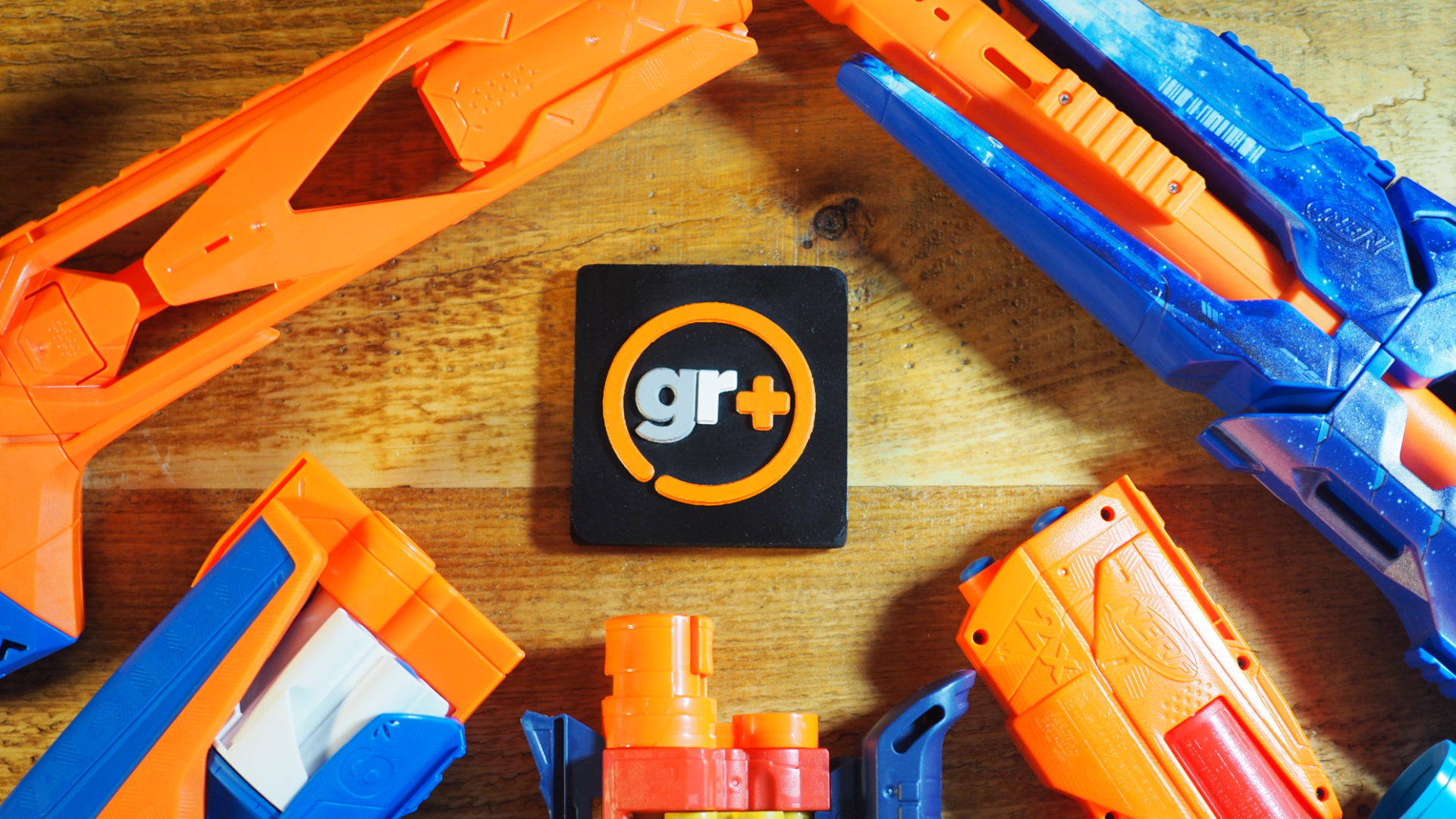A series of Nerf blasters surrounding the GamesRadar+ logo, all on a wooden surface