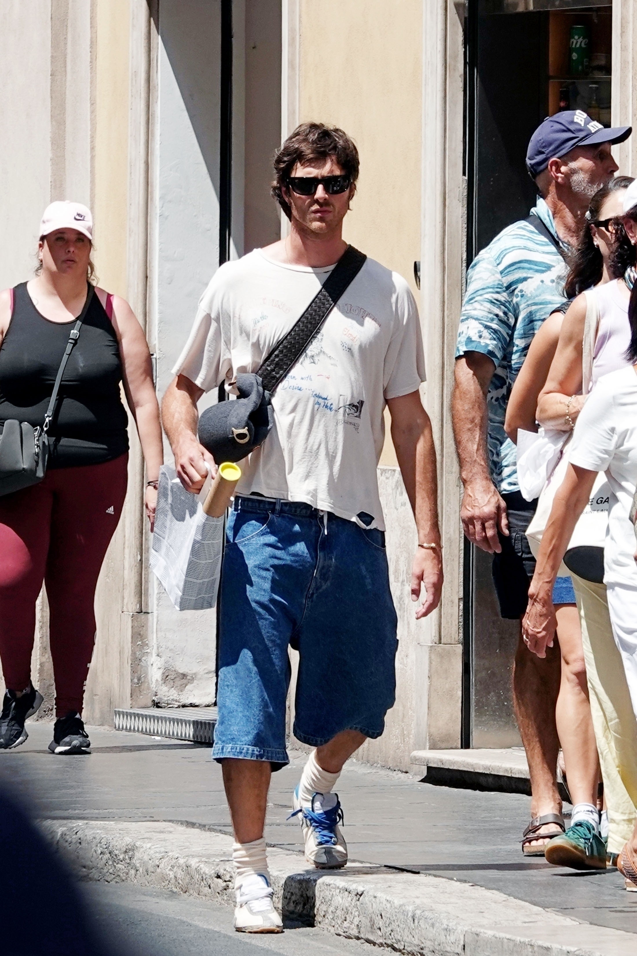 Jacob Elordi steps out in Rome wearing long-line denim shorts, an oversized, ripped t-shirt and Maison Margiela Sprinter trainers.