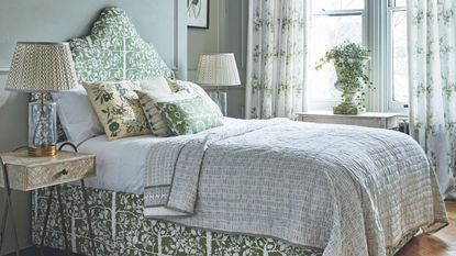 Green patterned bedroom with green patterned bed and cushions and large windows and white patterned curtains