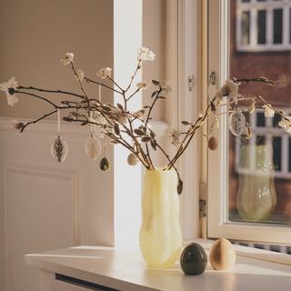 An Easter tree in a yellow vase on a windowsill