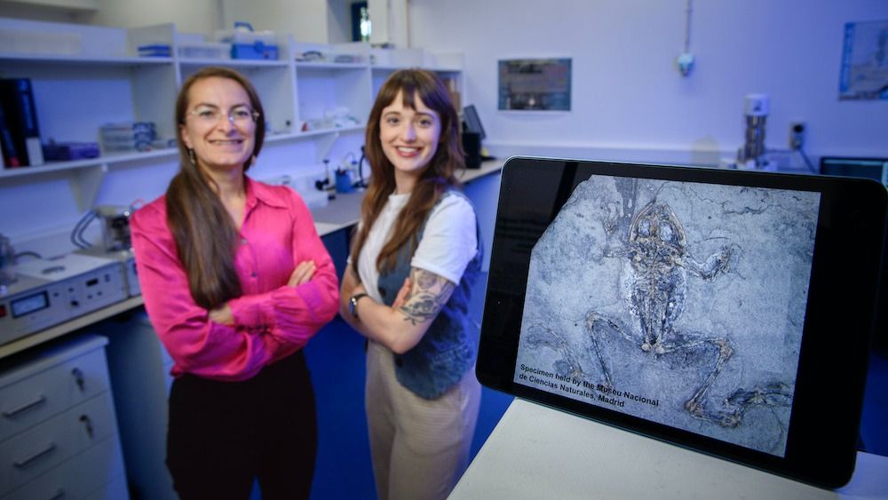 Two women pose with a frog.