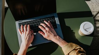 A close up of a person's hands typing on a laptop