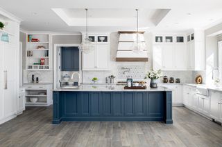 large farmhouse kitchen with blue island and white cabinets and cooker hood