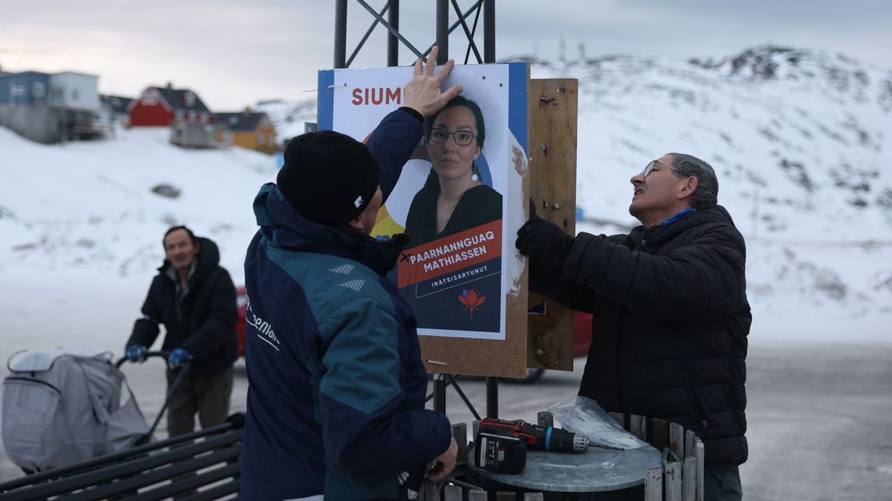 Siumut party candidate Bernhardt Olsen (right) and a volunteer hang campaign posters in Ilulissat, Greenland ahead of Tuesday&#039;s election