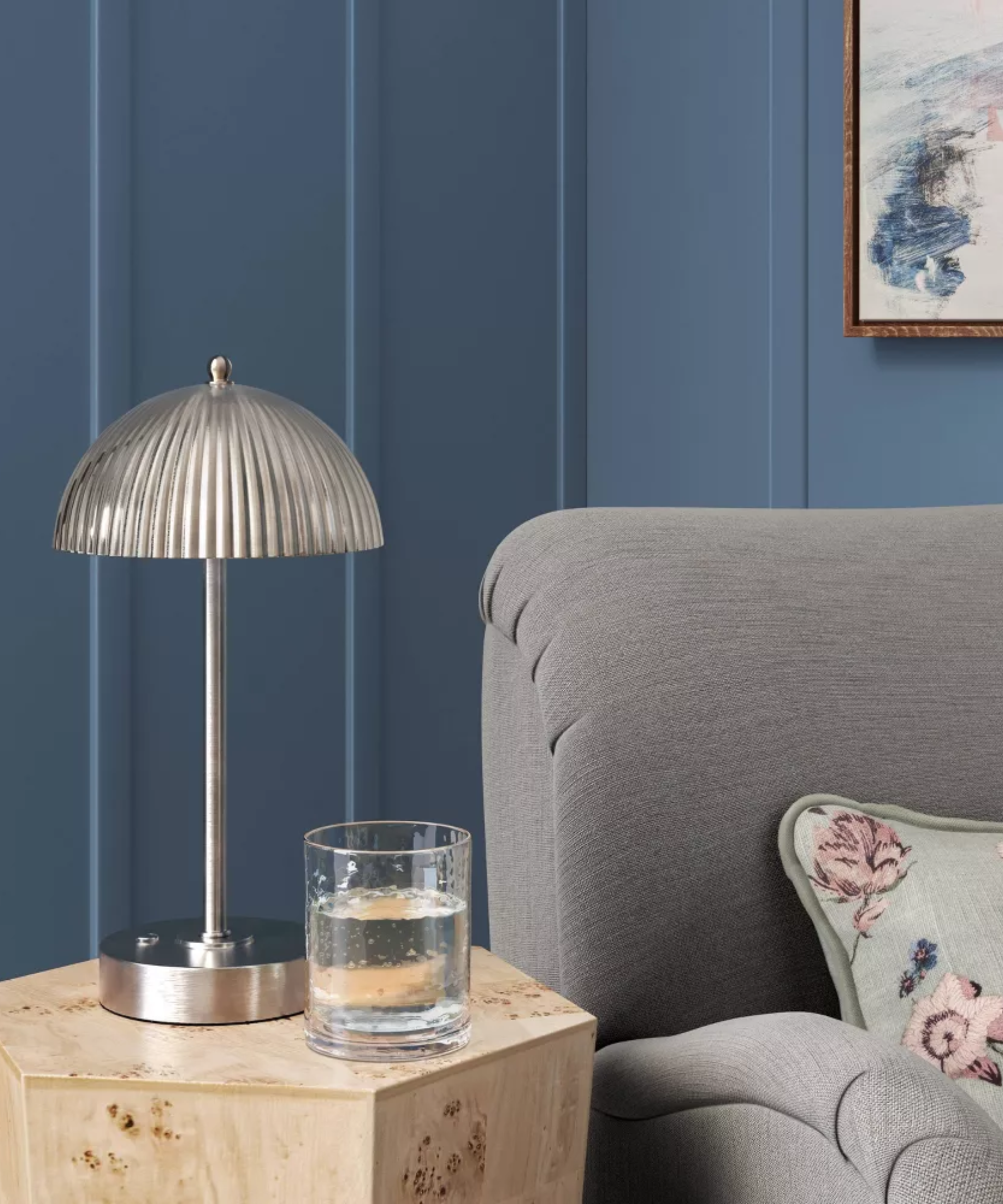 Antique-style fluted chrome portable lamp from Target sitting atop a burl wood side table alongside a gray accent chair