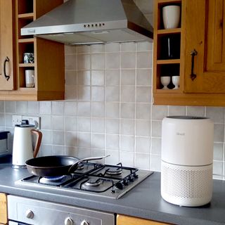 The Levoit Core 300S air purifier being tested whilst cooking in a kitchen with grey worktops and wooden wall cupboards