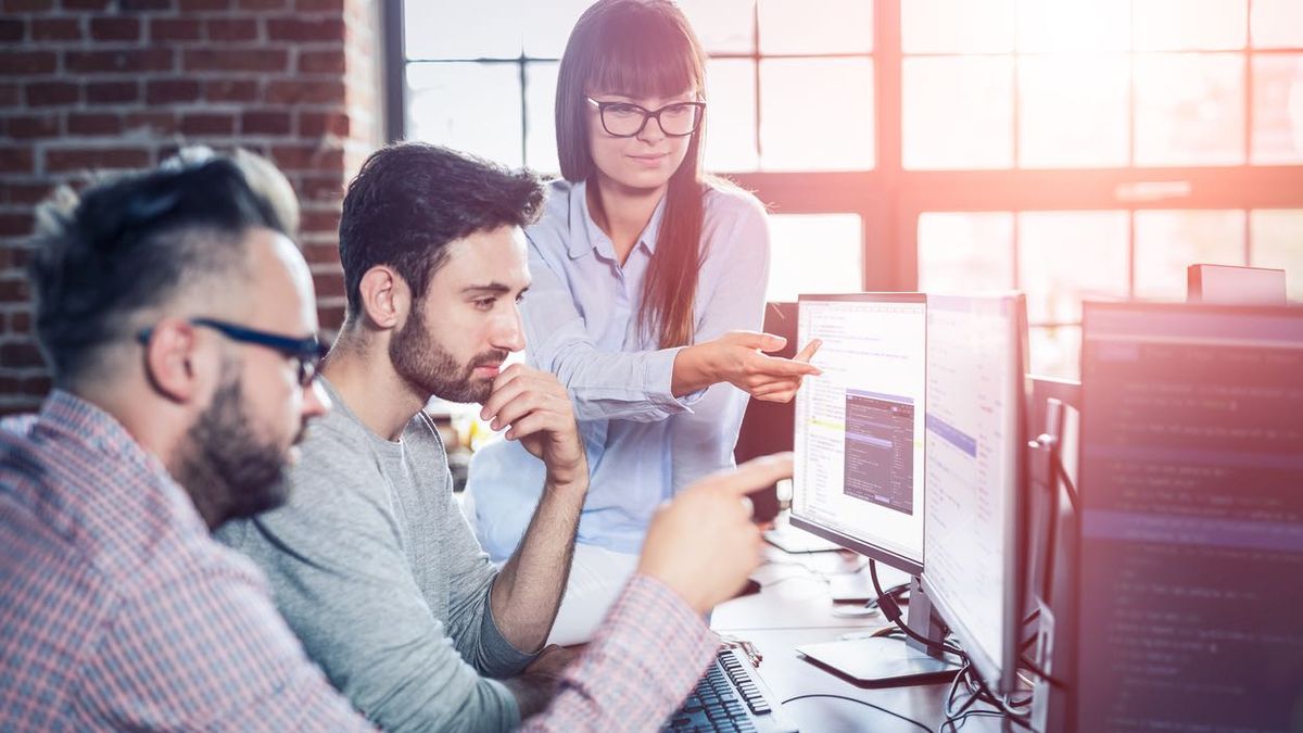 Three people working on a problem at a PC screen.