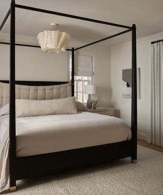 Dark bed frame with neutral linens and walls