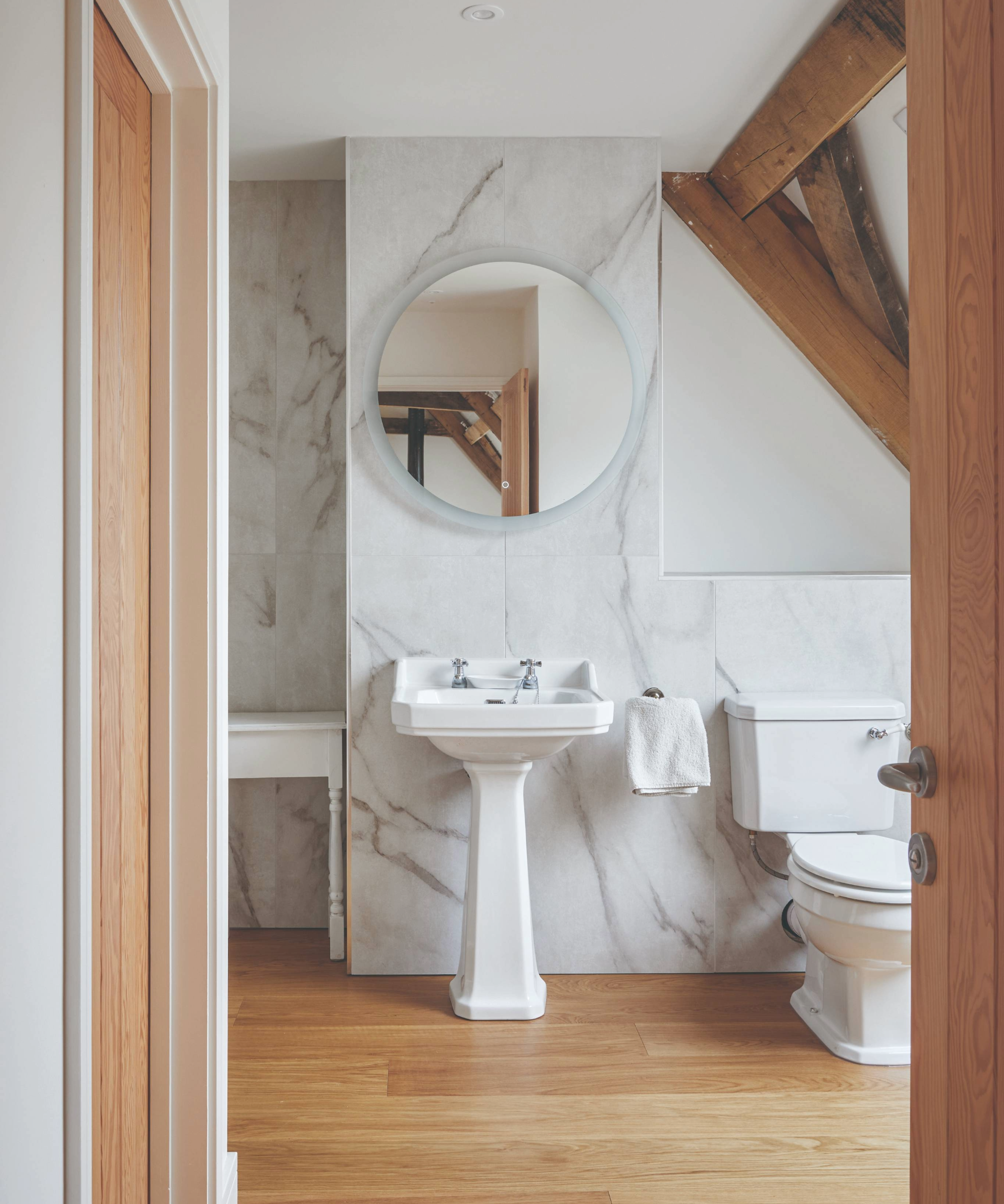 Toilet with marble paneling and wooden flooring