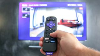 A Roku Voice Remote Pro with a Roku Ultra playing the Roku Camera channel in the background