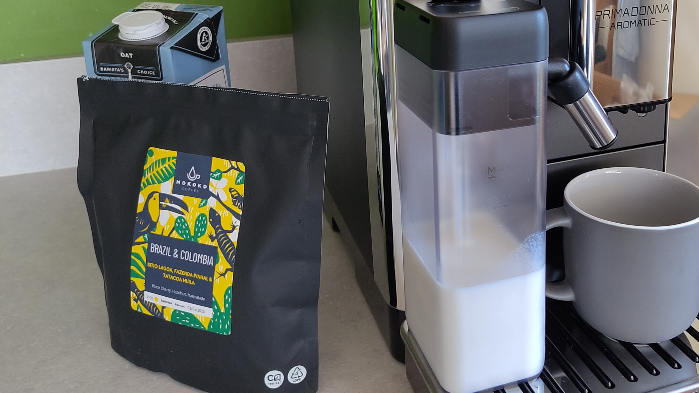Coffee beans beside De'Longhi Primadonna Aromatic coffee maker