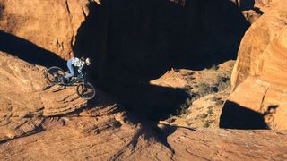 A woman rides down a desert rock slab