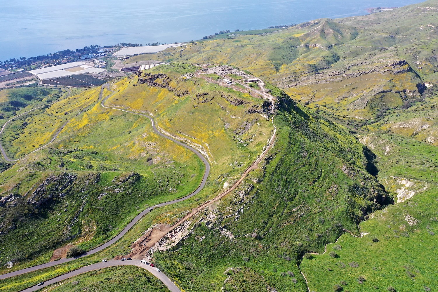 A bird's eye view of a green ride landcape with roads across the tall ridges