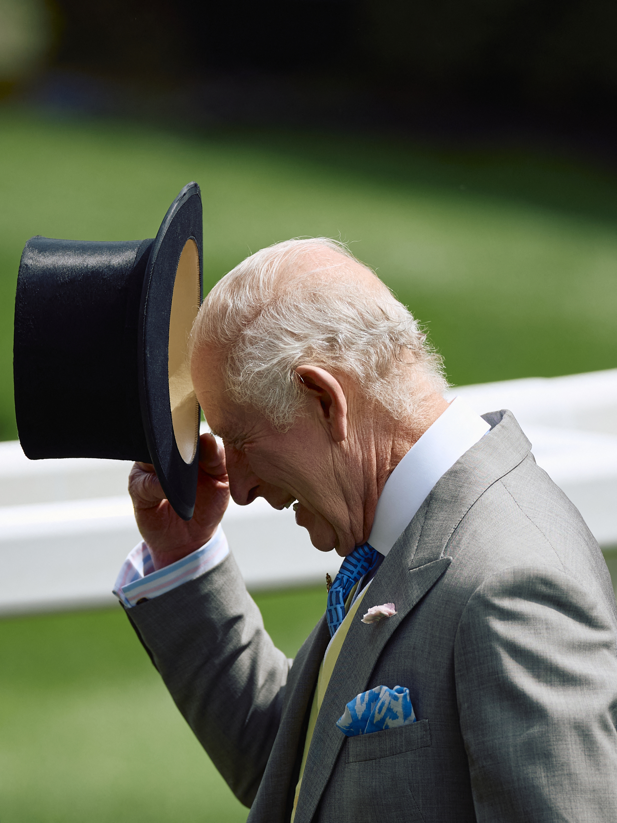 King Charles in morning dress tipping his top hat