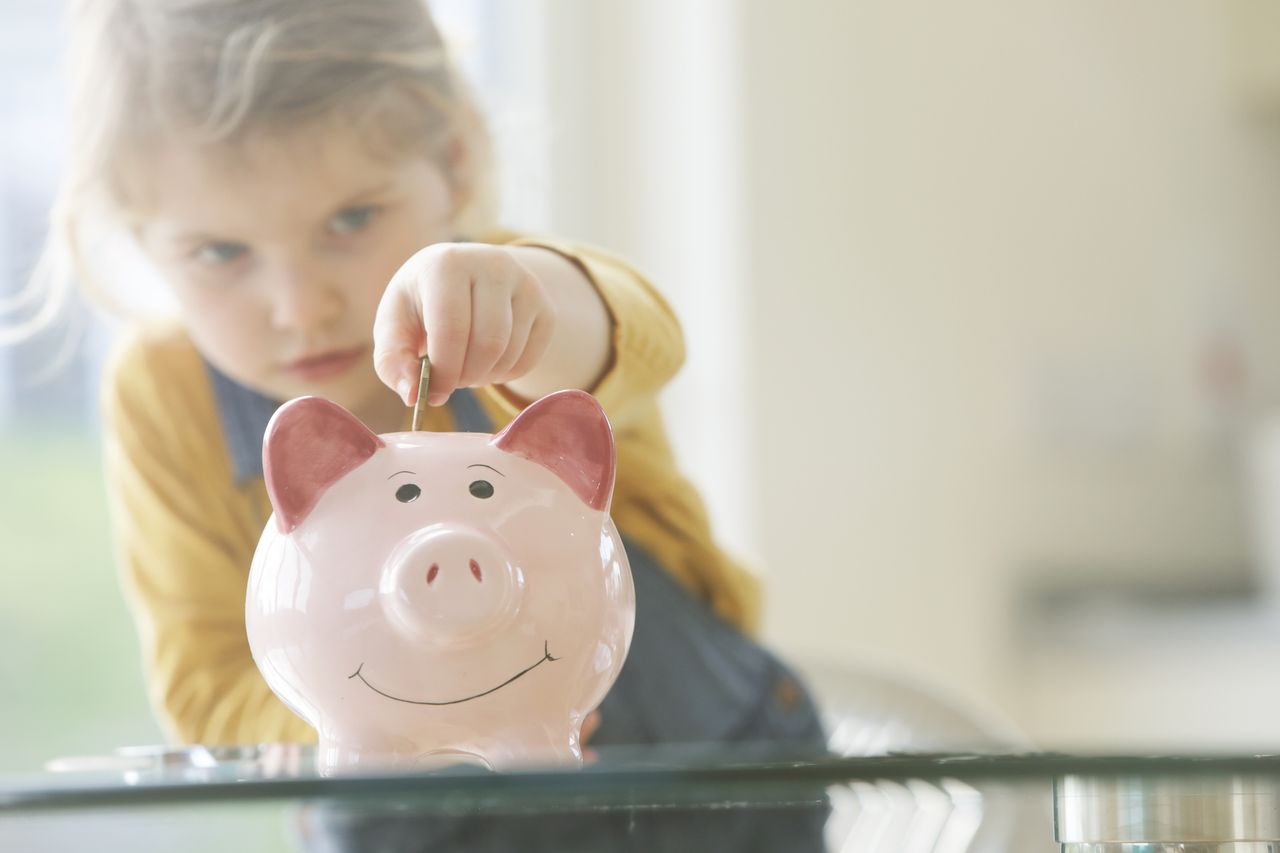 Child putting money in piggy bank