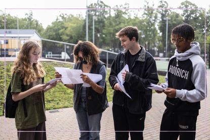 Four students holding pieces of paper on A level results day