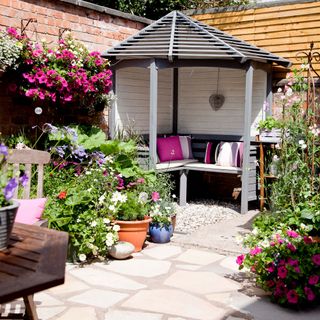 Wooden courtyard in summer garden, colourful flowers, stone concrete patio