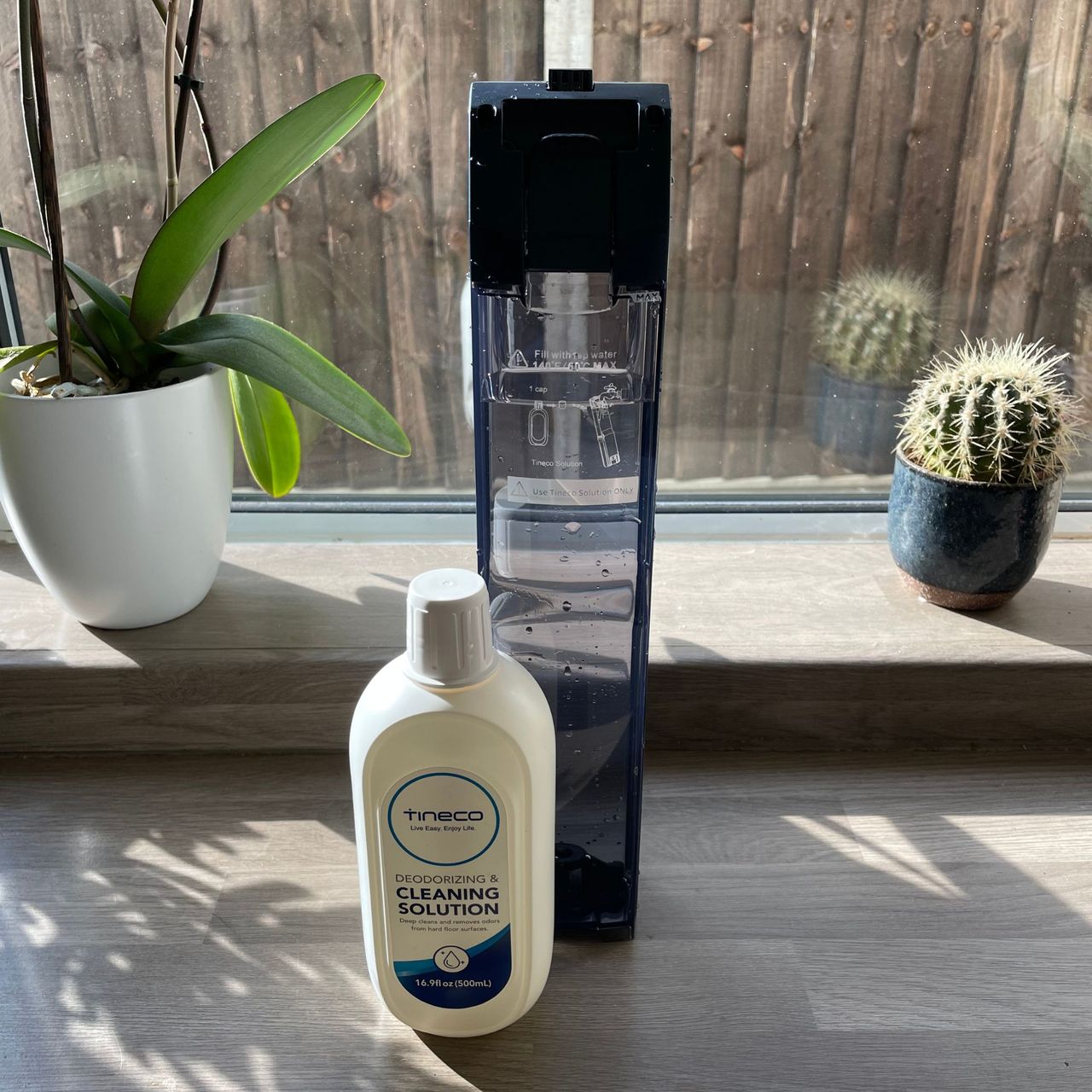 Tineco Smart Mop water container with a bottle of Tineco cleaning solution next to it