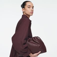 model wears wine-colored mono chrome outfit and a matching oversized clutch