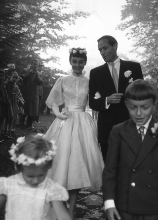 Film star couple Audrey Hepburn (1929 - 1993) and Mel Ferrer walk arm in arm on their wedding day in 1954