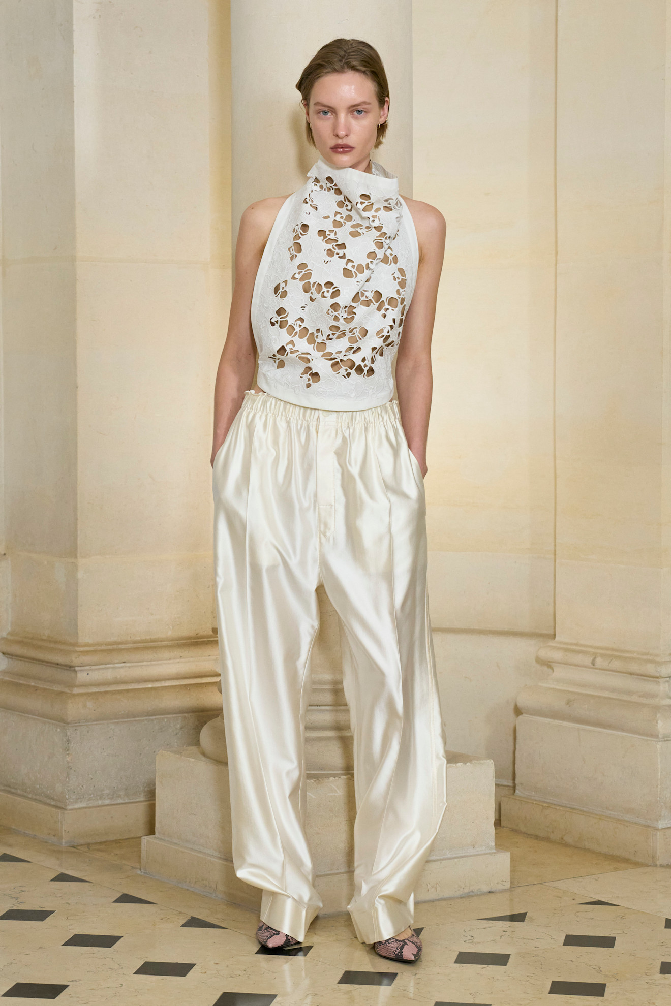 A model at the SS26 Carven show wearing a halter top and cream satin trousers.