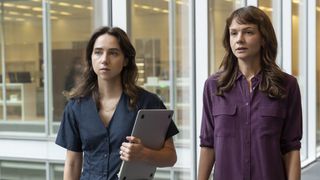 A still from the movie She Said featuring Carey Mulligan as Megan Twohey and Zoe Kazan as Jodi Kantor walking down a glass hallway.