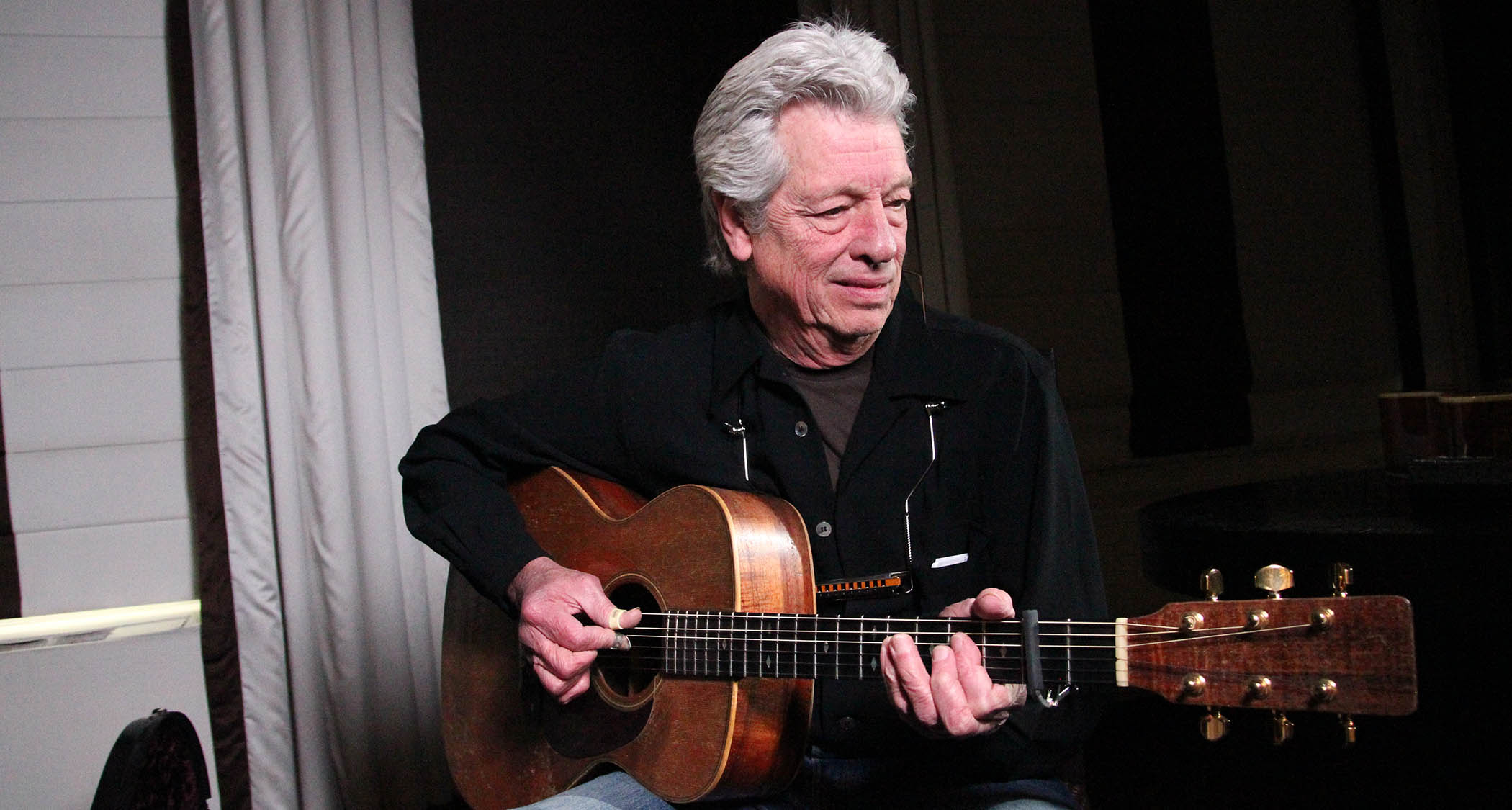 The late great John Hammond frets a chord on a capoed acoustic.