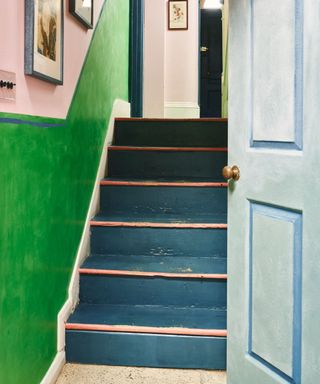 A green and pink entryway with a blue staircase and door