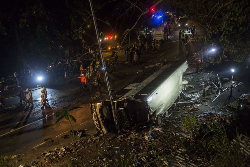 A bus lies on its side after a crash as firefighters works in Hong Kong on February 10, 2018. 