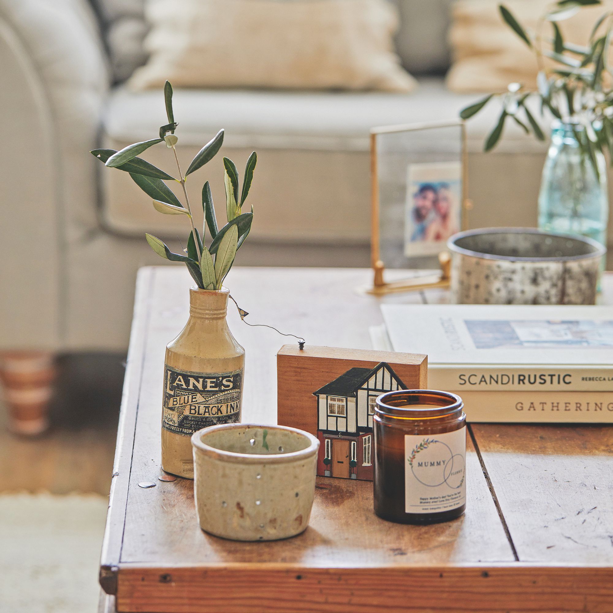 Wooden table with a vase, candles, books and photo frames on it